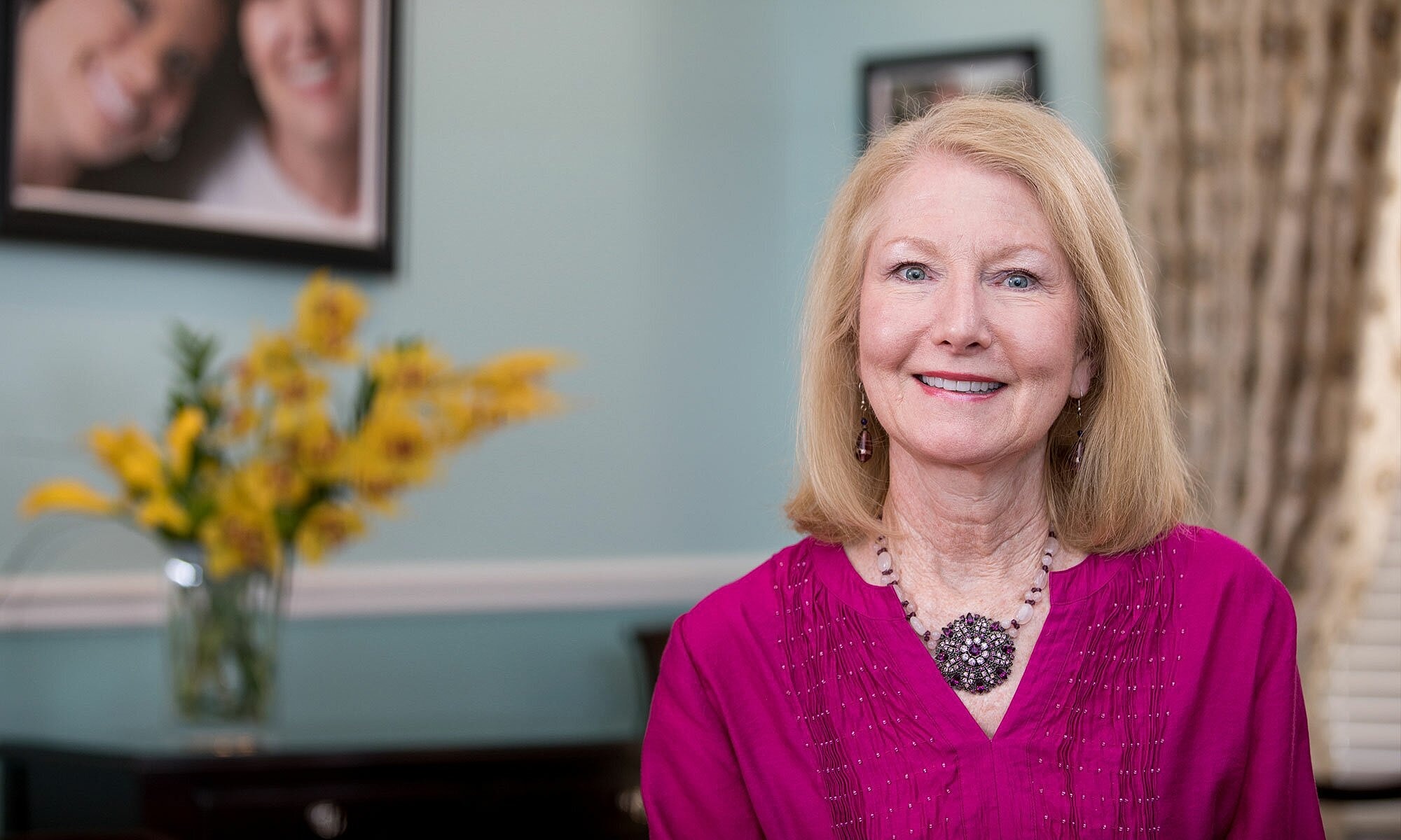 Smiling woman in pink top with floral background.